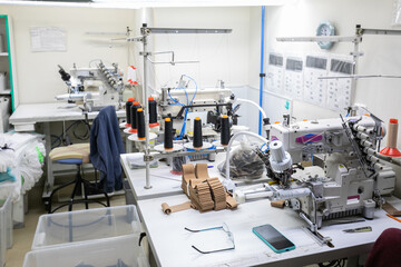 A seamstress's workplace at a textile factory with sewing machines and hosiery products