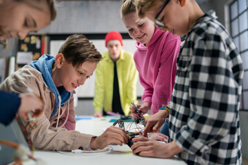 Group of kids working together on project with electric toys and robots at robotics classroom