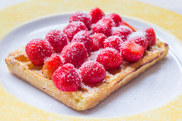 Warm Belgian waffle with fresh strawberries and suger on a plate