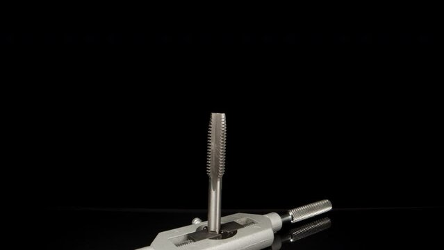 A tool for cutting threads in metal on a black table. Dolly slider extreme close-up. Laowa Probe