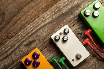 Three guitar pedals on wooden floor, flat lay