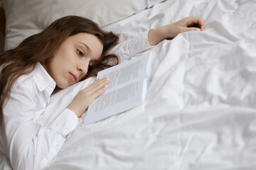 Teenage girl lying near the book on the bed in her dreams of the good