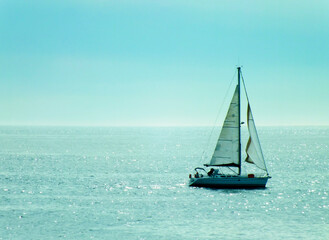 A sailing boat in a beautiful blue sea, a photo of a sailboat in turquoise ocean, sun rays hitting...