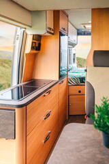 Interior of a camper van with kitchen and bed in the background