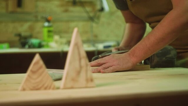 A mature carpenter makes works in his carpentry workshop, measures the wood by molting