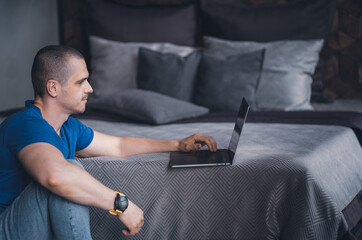 Adult man in blue t-shirt working on laptop