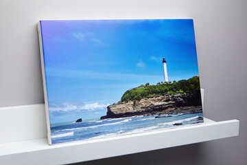 Canvas photo print with white edge and shelf hanging on grey wall