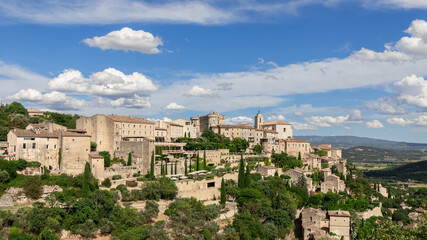 Fototapeta na wymiar Breathtakingly picturesque sky with floating white clouds over medieval Gordes village, rock and Luberon valley. Vaucluse, Provence, France
