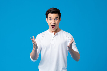 Surprised cheerful Caucasian man standing on blue background in light studio