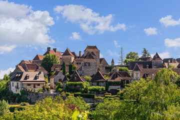 Fototapeta na wymiar Panoramic view of toy small medieval Loubressac village with stone houses with sloping roofs surrounded by lush vegetation. Lot, Occitania, France