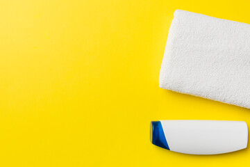 Cosmetic shampoo bottle mockup with towels on a colored table. Bathroom background, toilet accessories for hand and body care