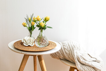 Home composition with flowers in a vase in the interior of a white room.