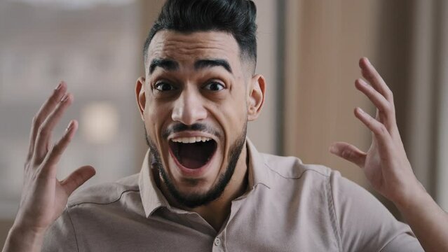 Close up shocked happy young hispanic male business man professional worker surprised looking at camera make big eyes rejoice victory amazed guy winner demonstrate wow reaction joyful face expression