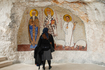 Pilgrim in front of an icon in Ostrog Monastery in Montenegro. Women are praying in Manastir...