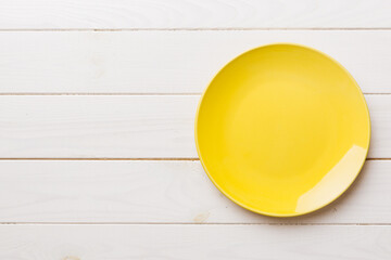 Top view of empty yellow plate on wooden background. Empty space for your design