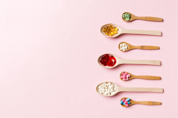 Top view Variety of vitamin and mineral pills in wooden spoon on Colored background. Top view of assorted pharmaceutical medicine pills. Dietary supplement healthcare product