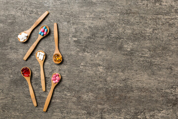 Top view Variety of vitamin and mineral pills in wooden spoon on Colored background. Top view of assorted pharmaceutical medicine pills. Dietary supplement healthcare product