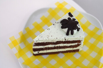 fresh chocolate peppermint cake, placed on a yellow and white plastic plate on a white ceramic plate, white background