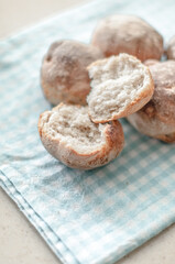 Fresh baked wheat-rye buns with one split in half on a cotton napkin.