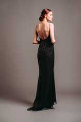 Black evening dress. Elegant lady in full-length backless sleeveless vintage gown with straps....