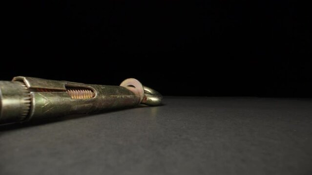 Metal anchor bolt on black table. Dolly slider extreme close-up. Laowa Probe