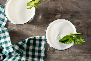 Ayran drink with mint and cucumber in glass on wooden table. Top view