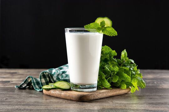 Ayran drink with mint and cucumber in glass on wooden table. Copy space