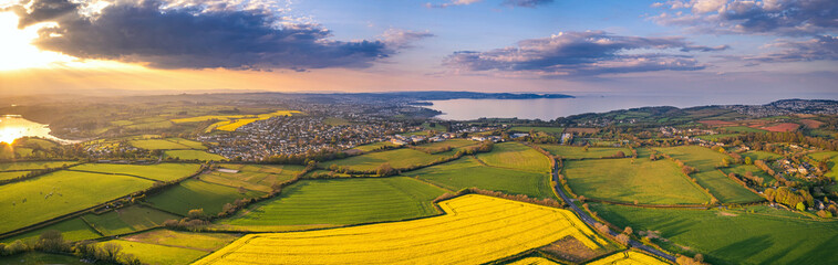 Fototapeta na wymiar Sunset over Rapeseed fields and Farmlands from a drone, Paignton and Brixham, River Dart, Devon, England