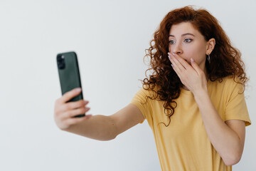 Naklejka premium young woman with red hair making selfie or video call on white background
