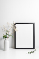 Portrait frame mockup in white minimalistic interior with flowers decorations
