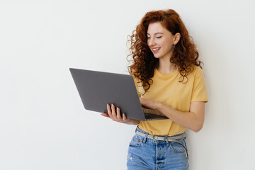 Smiling young woman student holding laptop and looking at camera on isolated white background.