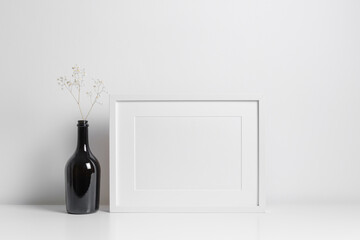 Horizontal frame mockup in white minimalistic interior with dark bottle decorations