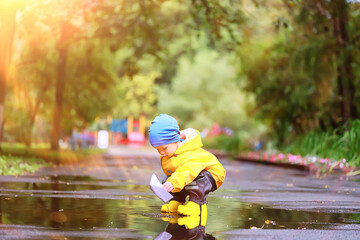 paper boat puddle game, boy seasonal autumn look raincoat, yellow rubber boots, outdoor game