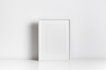Vertical blank frame mockup in white minimalistic interior for artwork, print or photo presentation