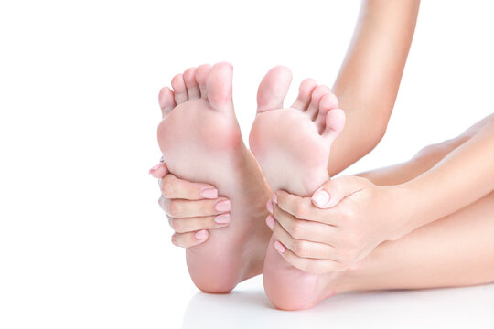 Feet Therapy Concepts. Closeup Image of Soft and Beautiful Female Foot While Hands Touching Foot While Massaging Legs Placed Over Pure White Background.