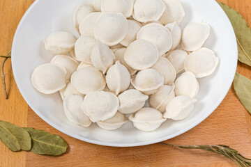 Uncooked frozen meat dumplings on dish, fragment close-up