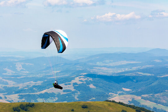 paragliding above the mountain valley. extreme outdoor sports. adventure and travel concept. clouds on the sky in summer