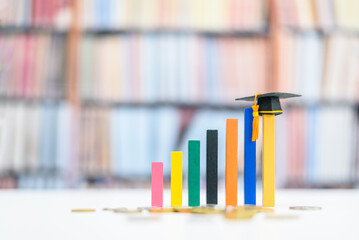 Graduate study abroad program for higher degree knowledge, education concept : Black graduation cap on increasing bar graph, depicting strong effort for students who study hard for a future career. - obrazy, fototapety, plakaty