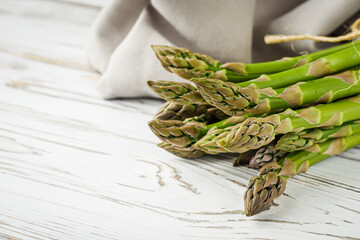 raw green asparagus on a white rustic wooden background