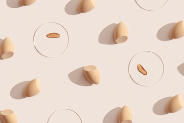 Makeup sponges for foundation cream, samples on glass disk on beige color background with shadows....