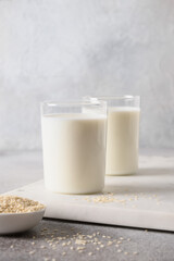 Sesame milk in two glasses on gray background. Close up. Vegan non dairy alternative plant based milk. Vertical format.