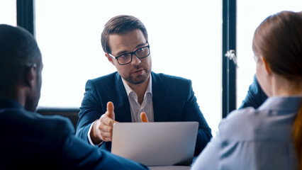 Fototapeta na wymiar Businessman in suit talking in meeting with team using computer