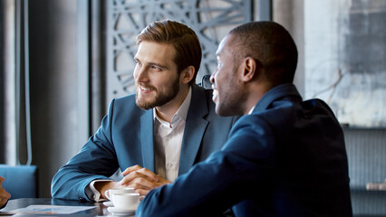 Two laughing young businessmen in suits at a meeting - 501096798