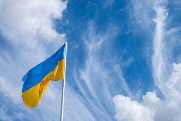 Flag of Ukraine fluttering in the wind on a white cloudy sky day.