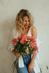 Young beautiful blonde woman with flowers on a light background