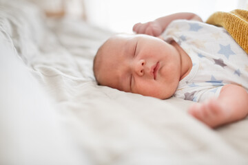 Cute sleeping chubby baby in a bed on a linen bedspread, a baby with chubby cheeks sleeps on a big bed