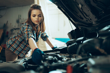 Destroying gender stereotypes. Young woman auto mechanic working at auto service station using...