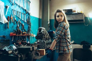 Female auto mechanic, beautiful young girl in working process at auto service station, indoors....