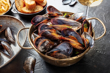 Mussels dinner in a French restaurant, with wine and toasted bread, on a dark table