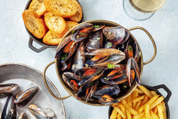 Belgian mussels with French fries and toasted bread, shot from above on a slate background